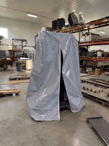 Gray tarp covering an object in a workshop.