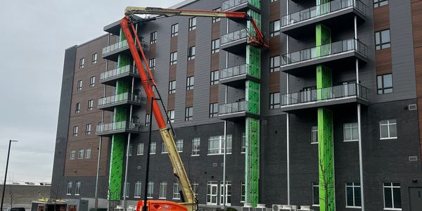 Construction workers using a boom lift on a multi-story building facade.