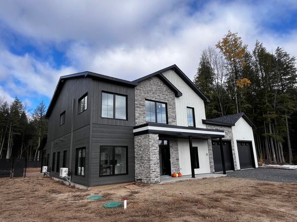 Modern two-story house with black and white exterior and stone accents.
