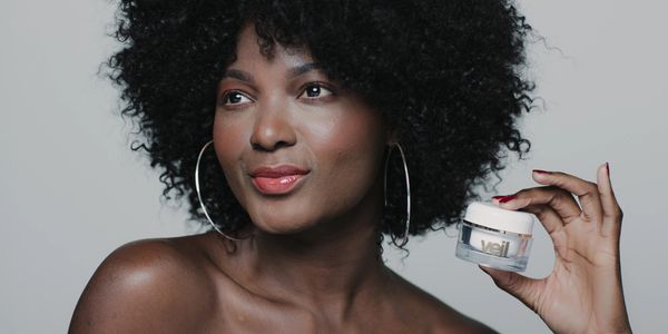 Woman uses Veil Cover Cream on face and holds professional jar in her hand