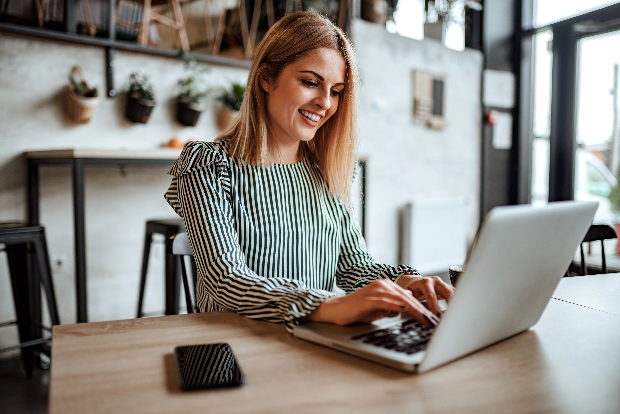 Smiling woman typing on laptop indoors