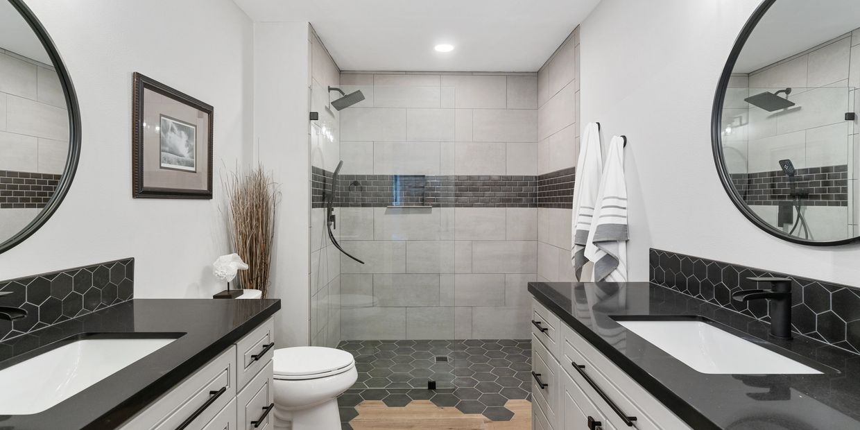 Modern bathroom with black hexagonal tiles and dual sinks.