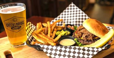 Burger with fries, dipping sauces, and a glass of beer - Breckenridge Taphouse Restaurant & Bar