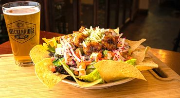 Nachos topped with grilled chicken with a glass of beer. - Breckenridge Taphouse Restaurant & Bar