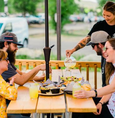 Friends enjoying dining outdoors with drinks and food - Breckenridge Taphouse Restaurant & Bar