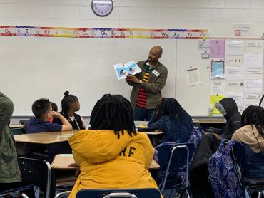 Teacher reads a book to attentive students in a classroom.