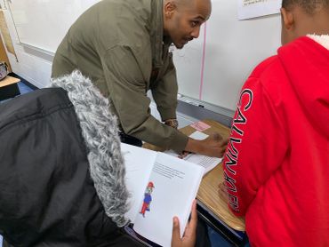 Teacher assisting students with reading and writing in a classroom.
