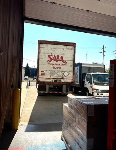 Freight truck backed up to warehouse to receive pallets of beverages.