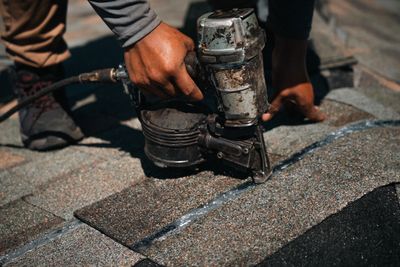 Roofer using a nail gun to perform a shingle roof repair