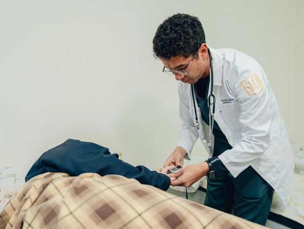 Doctor checking patient's pulse or oxygen level in a clinical setting.