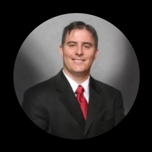 Man in a suit with a red tie smiling.