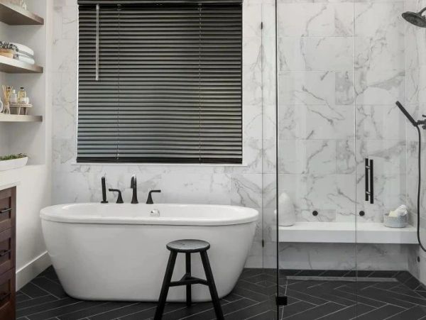 Modern bathroom with white tub and black accents.