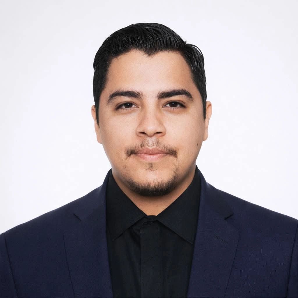 Professional headshot of a confident man in a dark suit against a white background.