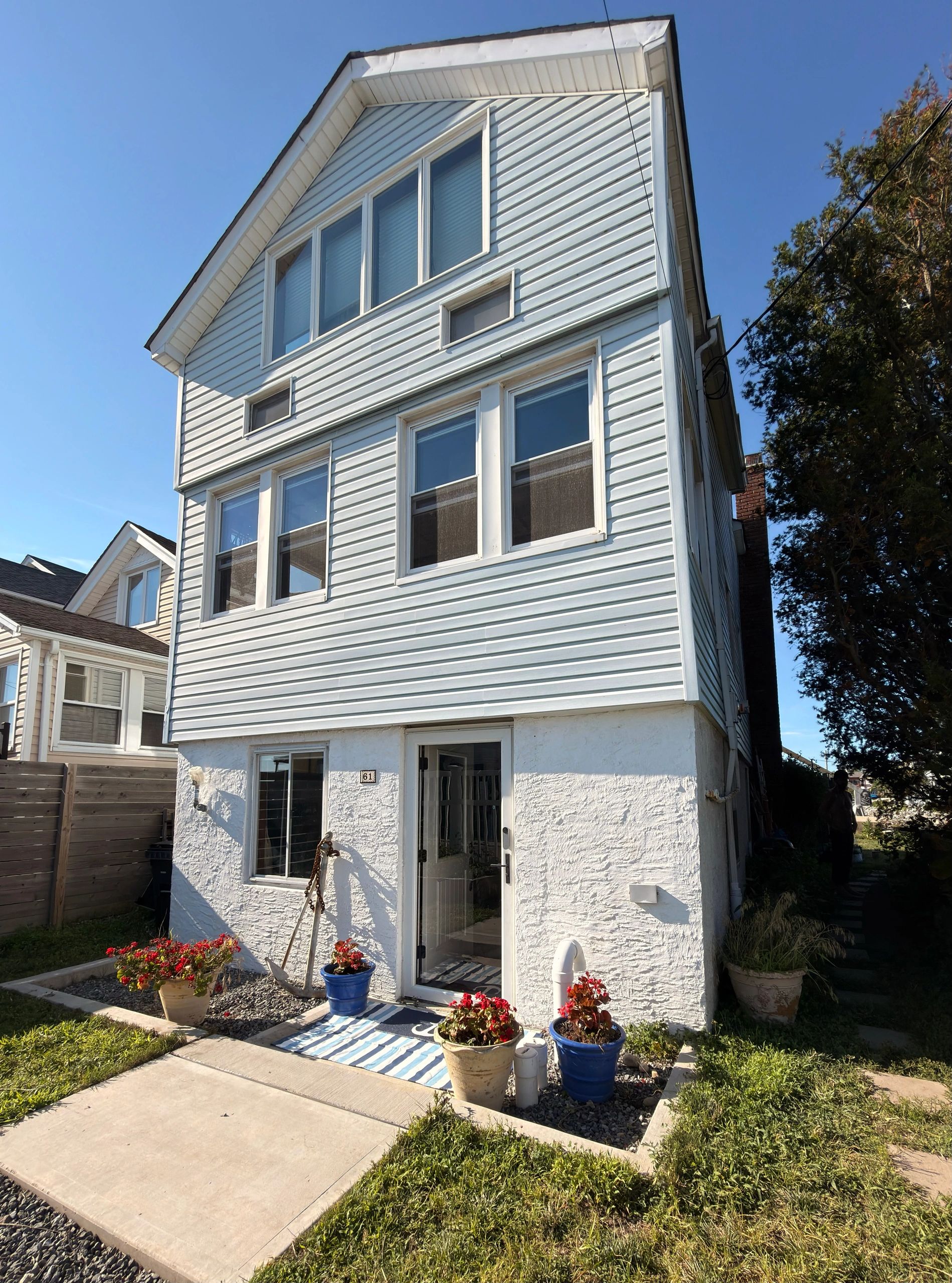 White house exterior with blue siding and potted flowers.
