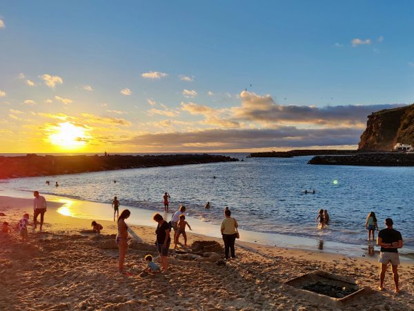 Pessoas aproveitam o pôr do sol na praia.