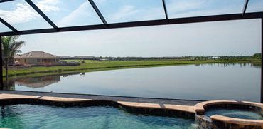 Pool and hot tub overlooking a serene lake and suburban houses.
