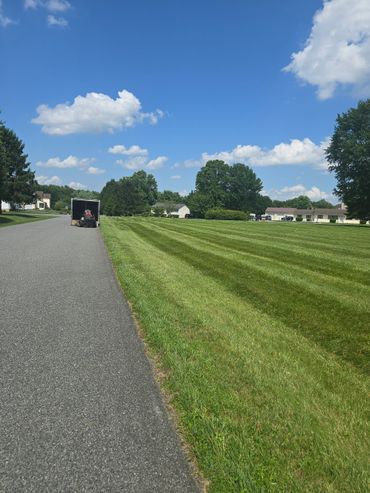 Lawn mower unloading on a sunny suburban street with freshly cut grass.