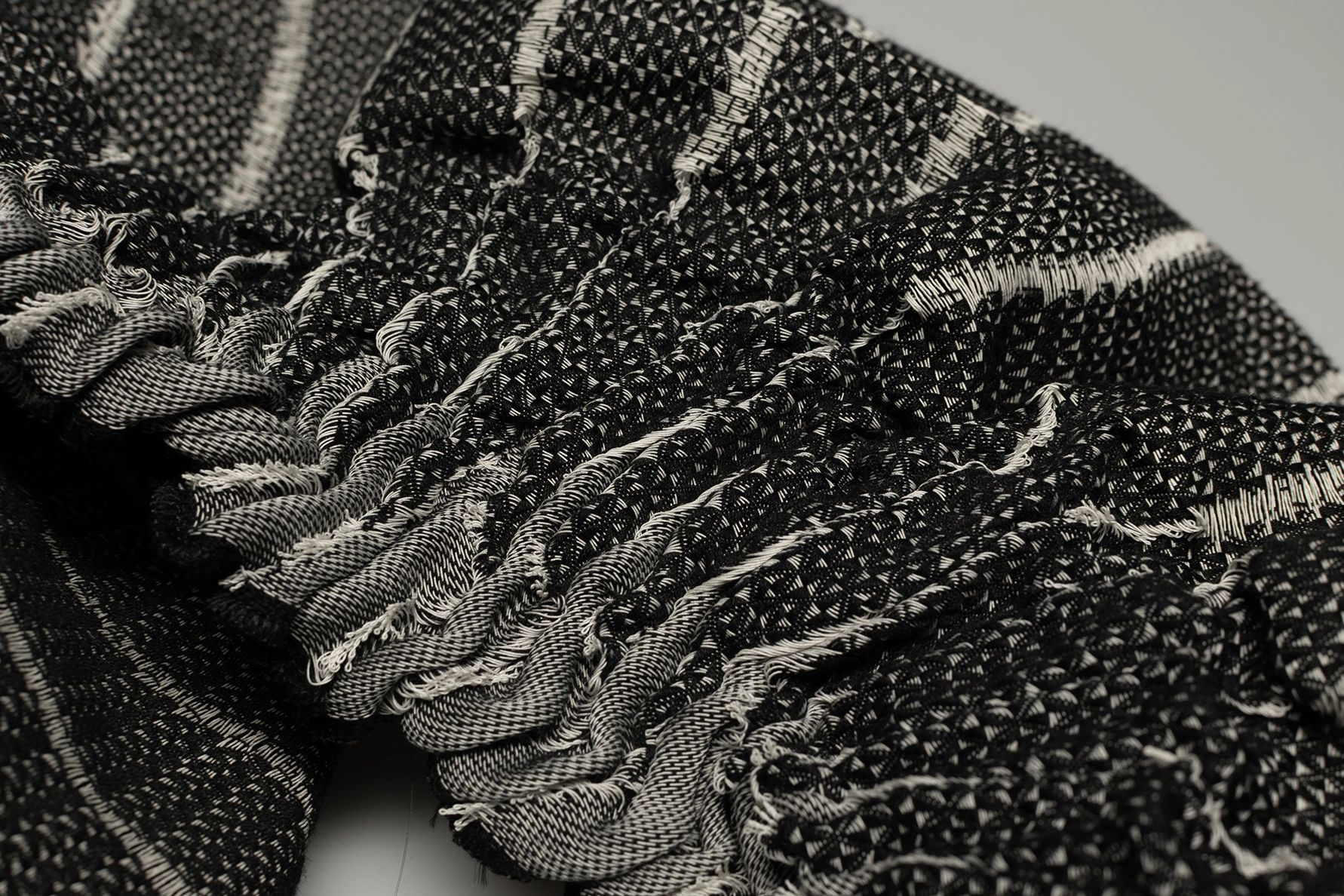 Close-up of intricately woven black and white fabric with detailed patterns.