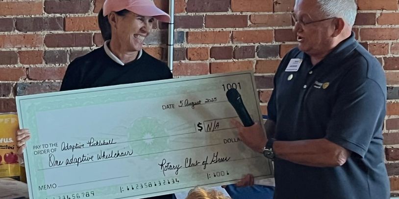 Man presenting large check to smiling woman.