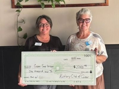 Two women with glasses smiling and holding a large check