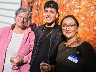 3 people smiling in front of fall backdrop