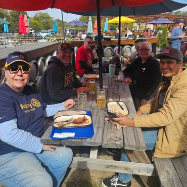 Group of people eating at picnic tables set under umbrellas