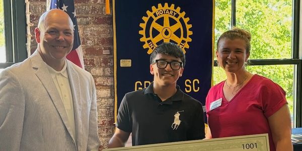 Three people smiling with youth holding a large check presented to him.