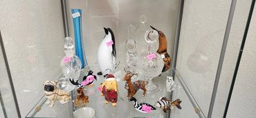 Glass and ceramic animal figurines with price tags in a display case.