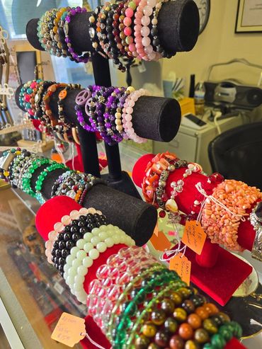 Colorful beaded bracelets displayed on black and red velvet stands.