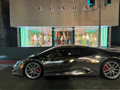 A silver Lamborghini in front of the Prada store