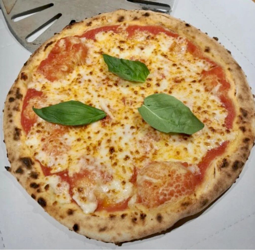 Picture shows a Margherita pizza with three pieces of fresh basil on the top
