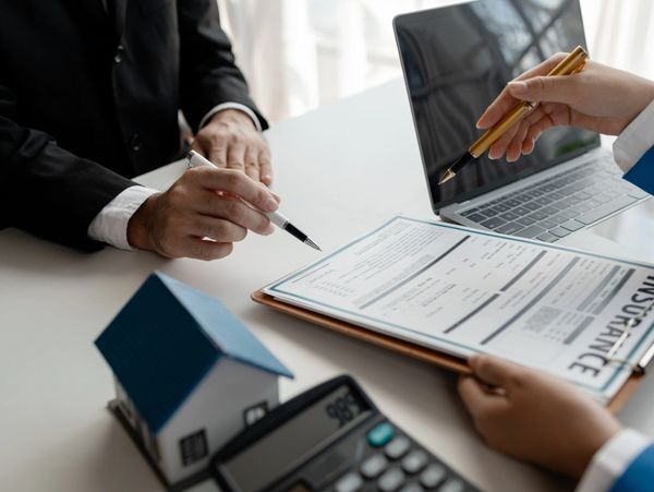 People discussing home insurance with model house.