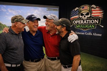 Four veterans laughing together at an Operation Mulligan golf event.