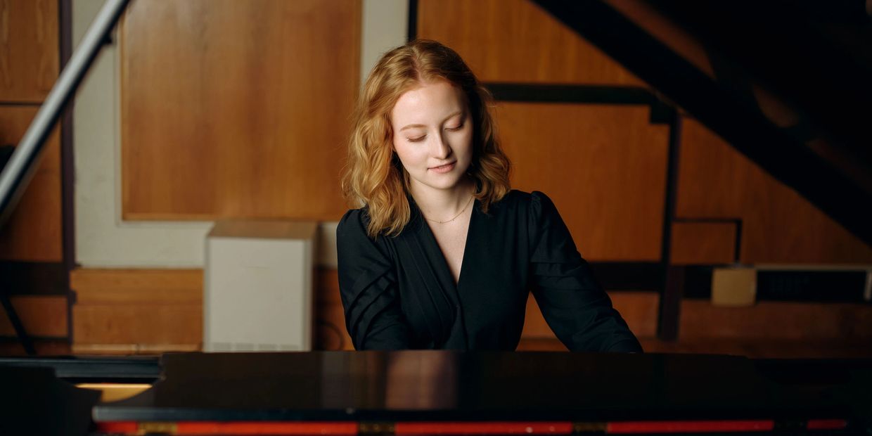 Woman playing piano with focused expression.