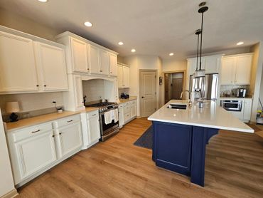 Modern kitchen with white cabinets and navy blue island.