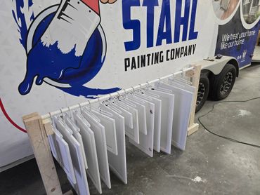 Painted cabinet doors hanging to dry in front of a painting company trailer.