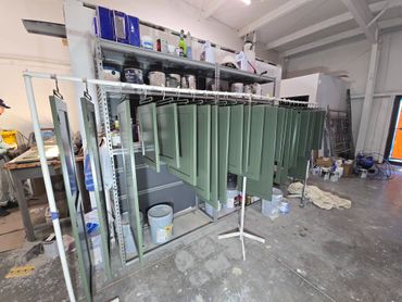 Green cabinet doors hanging to dry in a workshop.