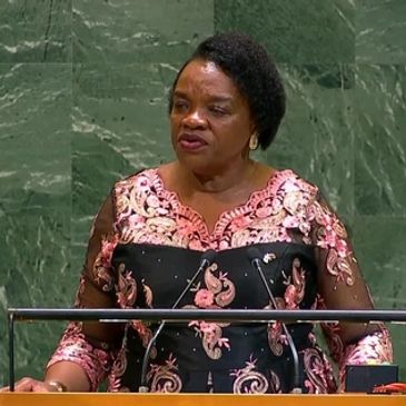 Woman speaking at a podium with a green marble background.