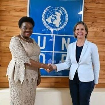 Two women shaking hands in front of a UNDP banner.