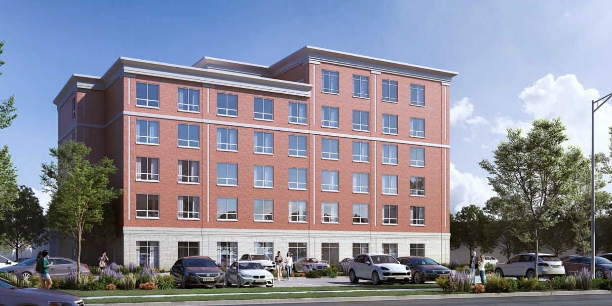 A modern five-story brick apartment building with parked cars in front.