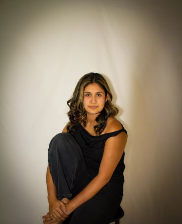Young woman in black top sitting and looking at camera.