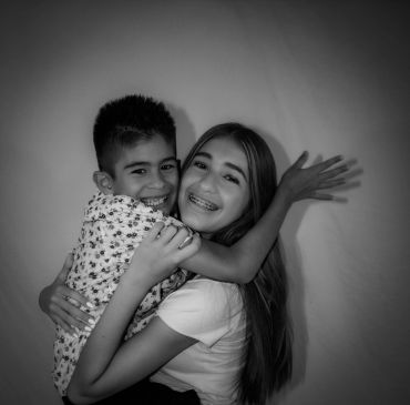 Two kids happily hugging in a black and white photo.