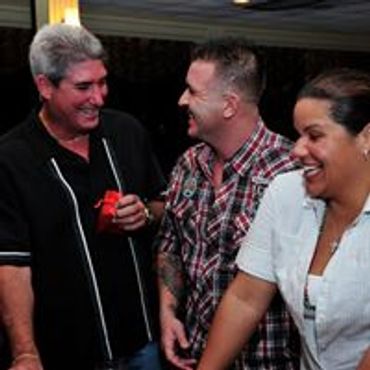 Three adults laughing and enjoying a casual moment together.
