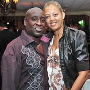 A smiling couple posing together at a social event indoors.