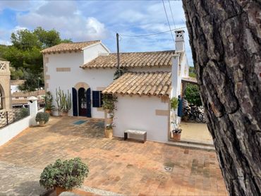White Mediterranean-style house with tiled roof and cactus plants.