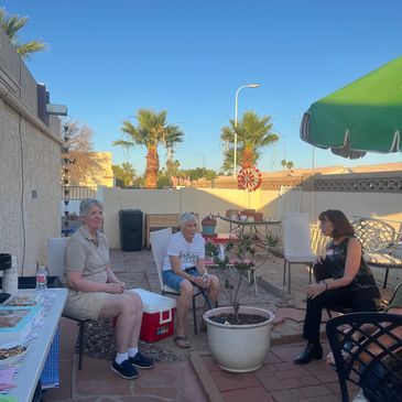 Three elderly women chatting outdoors on a sunny day.