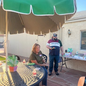 Two people enjoying an outdoor gathering under a sunshade.