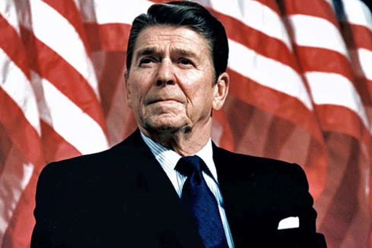 Ronald Reagan standing in front of a United States flag