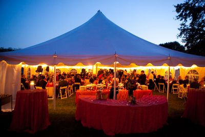 Tent at dusk with tables chairs and lines.