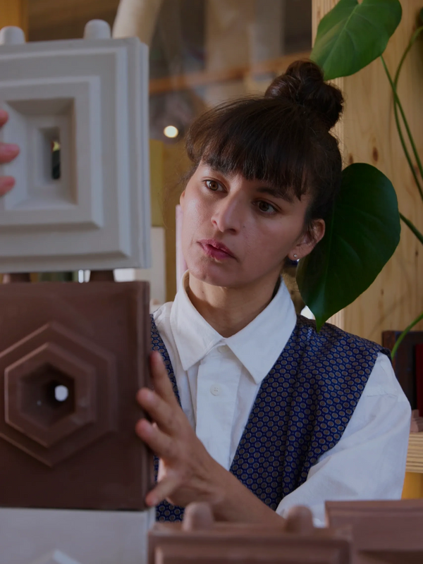 A woman carefully arranging geometric clay blocks indoors.